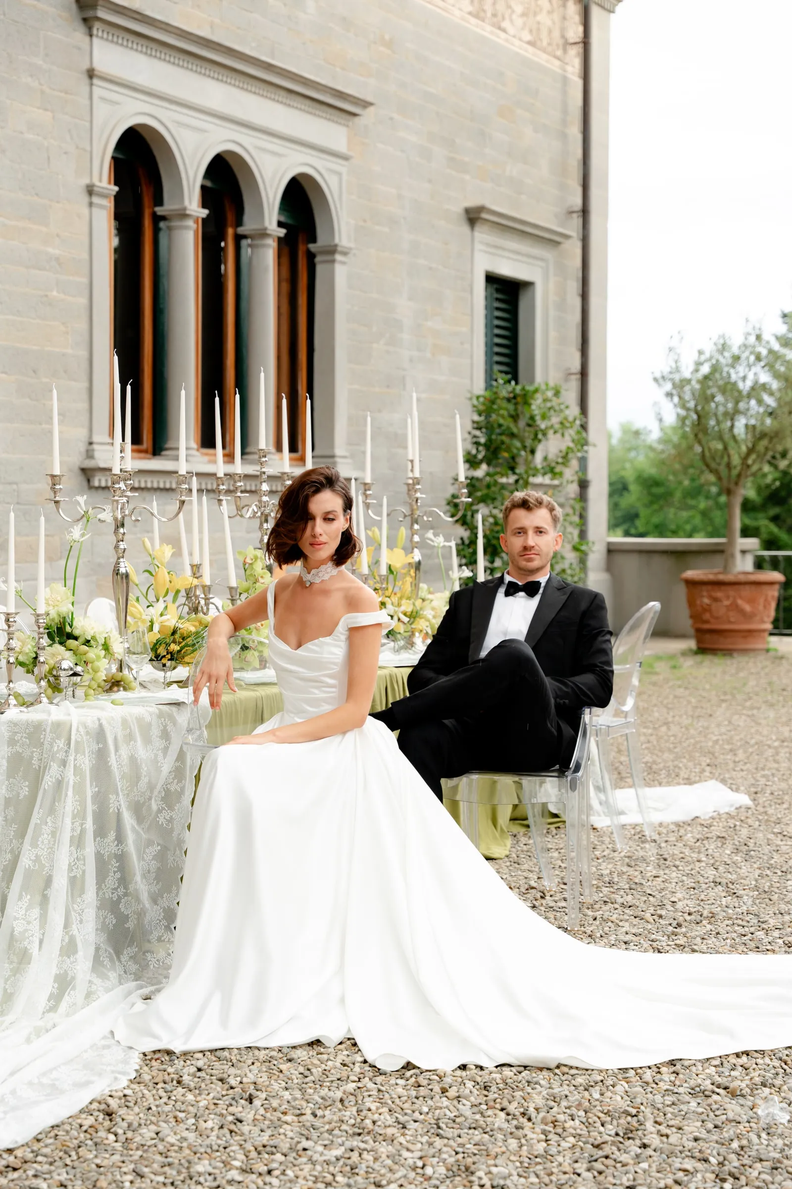 Bride and groom at a candlelit table outside an Italian villa, bridal makeup finished for evening light.