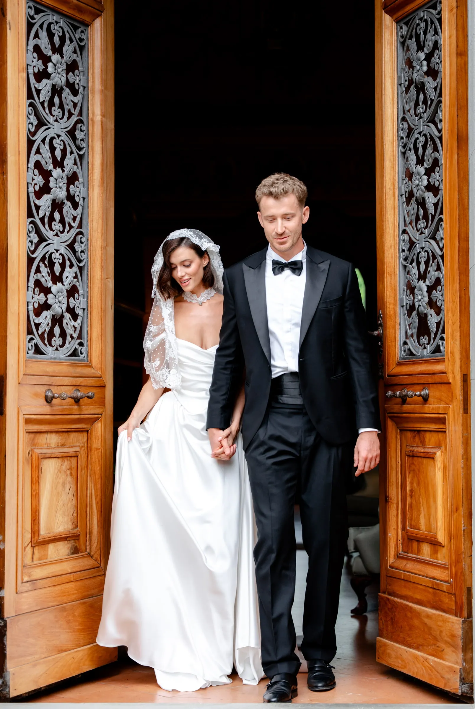 Bride and groom in a doorway, full-length, with makeup built to hold through a full wedding day.