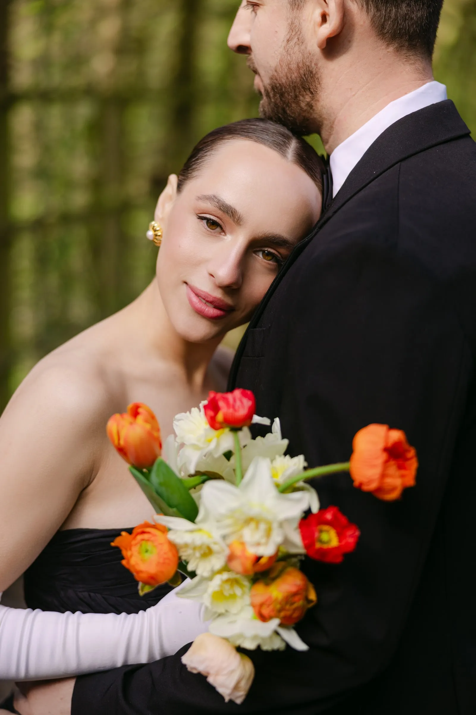 Editorial bride in a black gown holding tulips, with a graphic liner and a warm neutral lip.